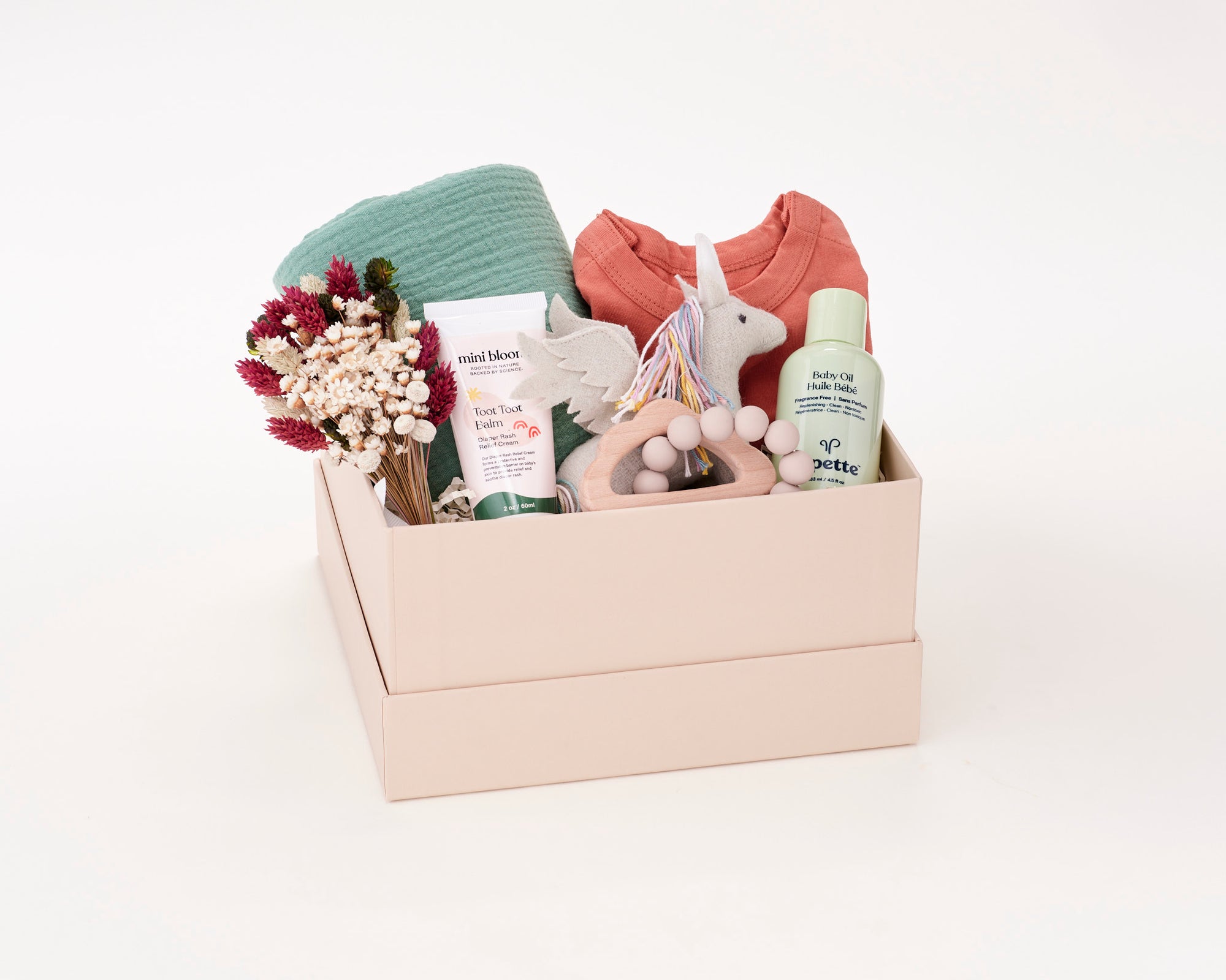 Baby Gift Box with a Roux baby swaddle, Tabeeze baby onesie, Pipette Baby Oil, Mini Bloom Toot Toot Diaper Cream, Olli Ella Stuffed Unicorn, and Marlowe and Sage Cloud Teether.